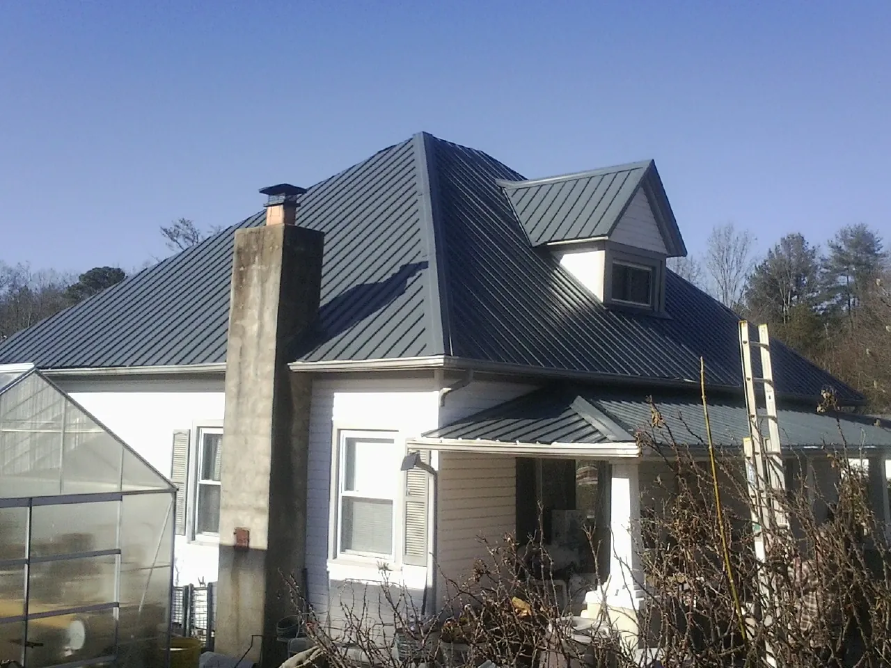 Dark blue standing seam metal roof on a white farmhouse with dormer — Slate & Tile Roof Repair by Roofing Brothers in Autaugaville