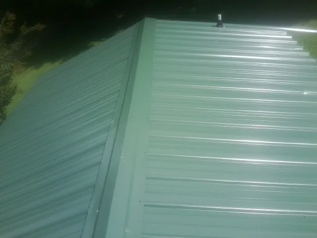 New green metal panels meeting at the ridge of a roof — Flat Roof Repair work by our crew in Autaugaville