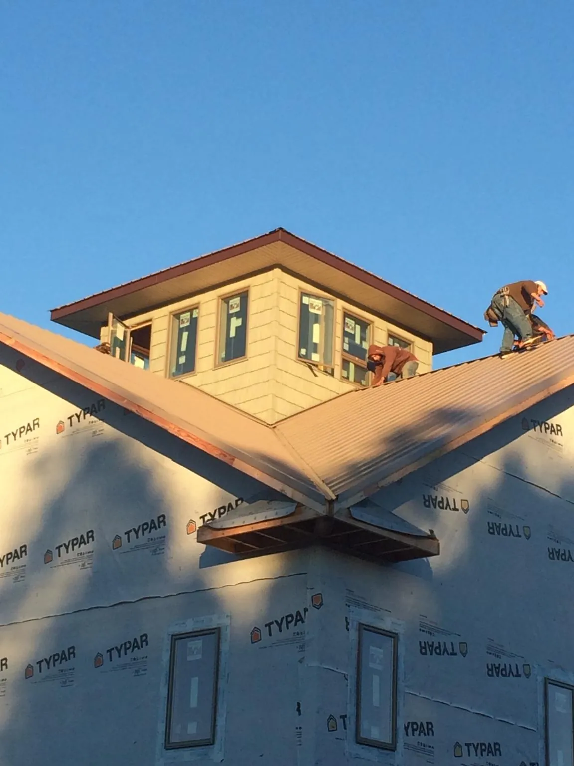 Roofers working around a rooftop cupola on a new metal roof at sunset — Roof Waterproofing in Autaugaville by Roofing Brothers